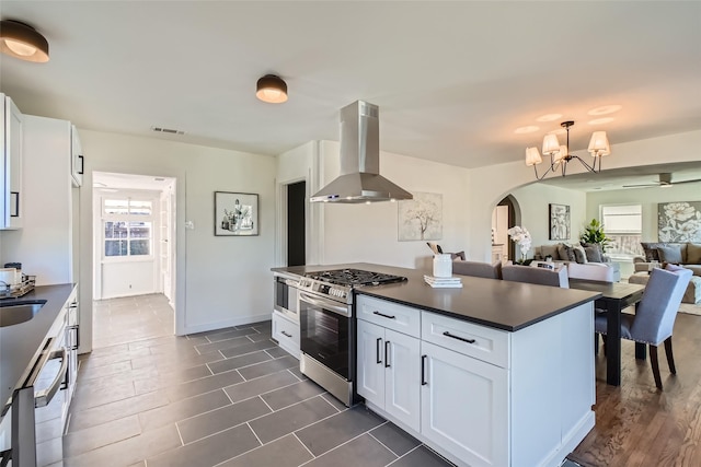 kitchen featuring white cabinetry, gas range, island range hood, and plenty of natural light