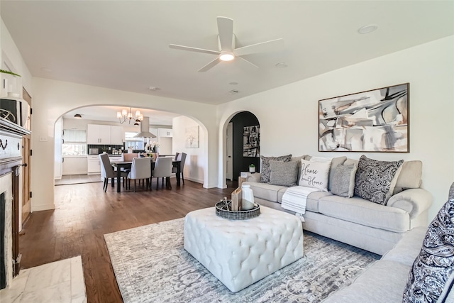 living room featuring dark hardwood / wood-style flooring and ceiling fan with notable chandelier