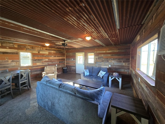 carpeted living room featuring ceiling fan, wood ceiling, and wooden walls