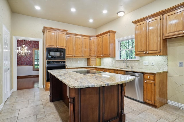 kitchen featuring sink, light stone counters, black appliances, a kitchen island, and a chandelier