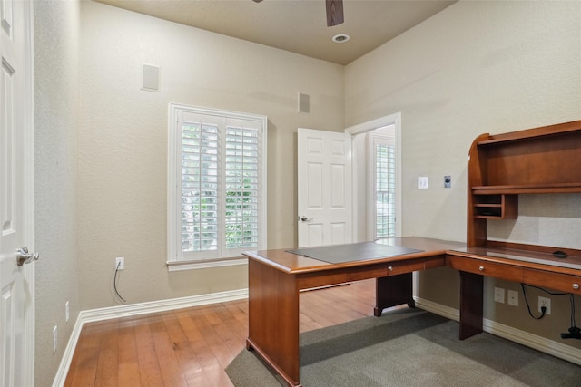 unfurnished office featuring ceiling fan, a healthy amount of sunlight, and light hardwood / wood-style flooring