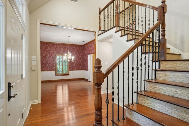 stairs featuring wood-type flooring and a notable chandelier