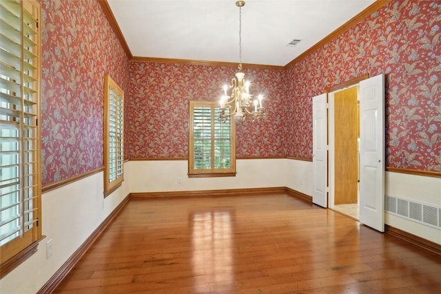 unfurnished dining area with crown molding, wood-type flooring, and a notable chandelier