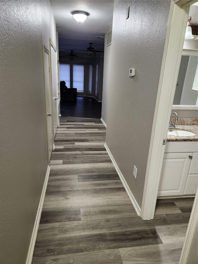 corridor with dark wood-type flooring and sink