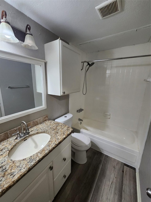 full bathroom with toilet, hardwood / wood-style flooring,  shower combination, a textured ceiling, and vanity