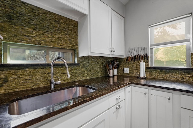 kitchen featuring sink, white cabinetry, tasteful backsplash, and dark stone counters