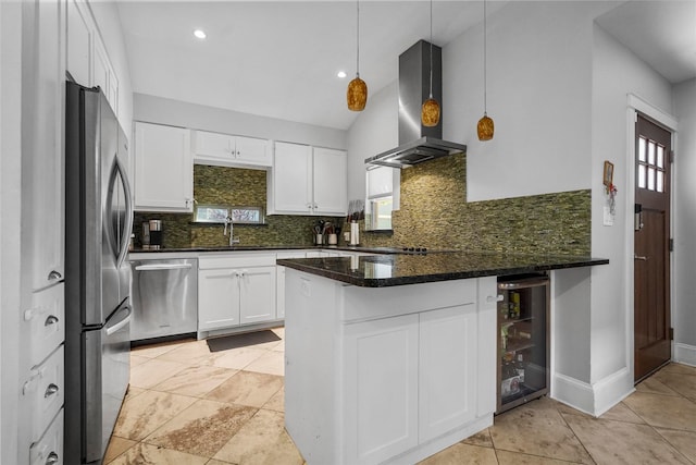 kitchen with kitchen peninsula, wall chimney exhaust hood, pendant lighting, stainless steel appliances, and beverage cooler