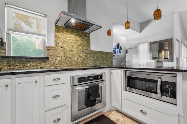 kitchen with decorative light fixtures, white cabinets, wall chimney range hood, and appliances with stainless steel finishes