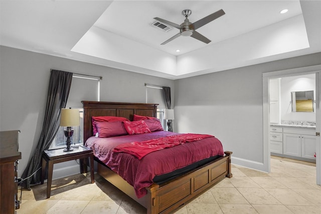 bedroom featuring ensuite bathroom, a raised ceiling, ceiling fan, and light tile patterned floors