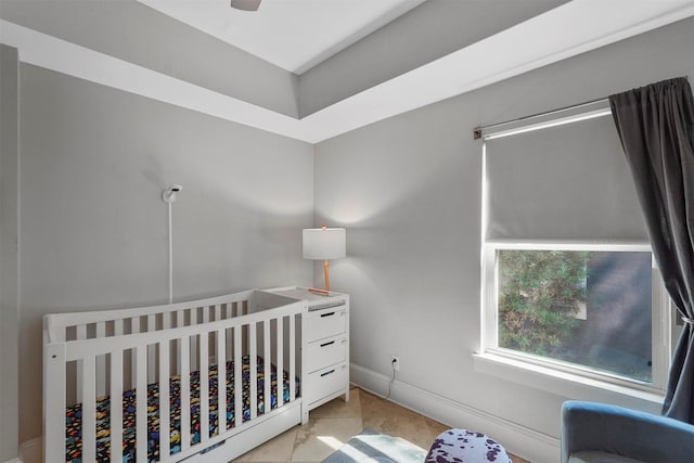 bedroom featuring light tile patterned floors, ceiling fan, and a nursery area