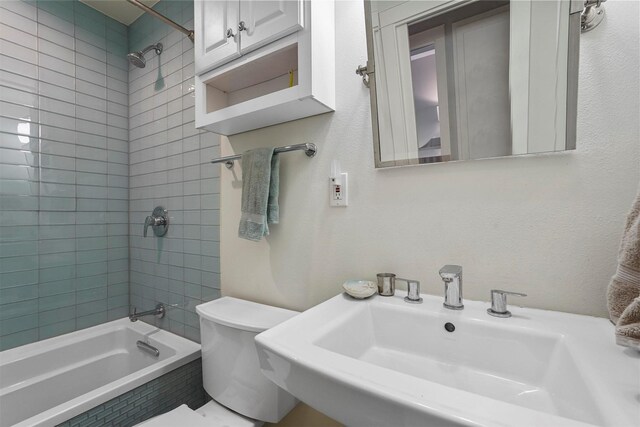 full bathroom featuring toilet, tiled shower / bath combo, and sink