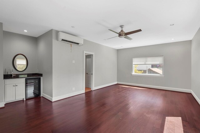 interior space with dark wood-type flooring, beverage cooler, ceiling fan, a wall mounted air conditioner, and sink