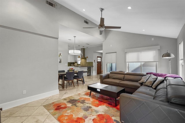 living room with ceiling fan, vaulted ceiling, a wealth of natural light, and light tile patterned floors