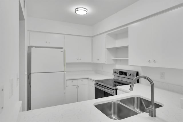 kitchen featuring sink, electric stove, white fridge, and white cabinetry