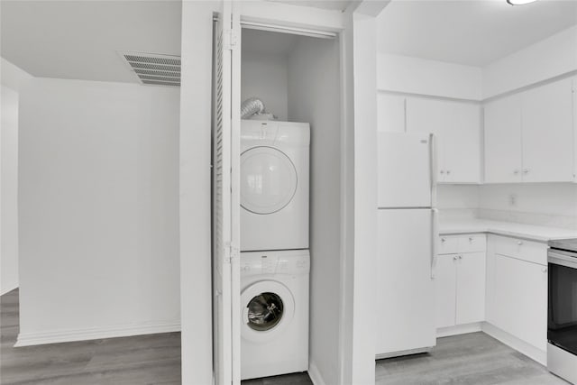 laundry room featuring light hardwood / wood-style floors and stacked washer / drying machine