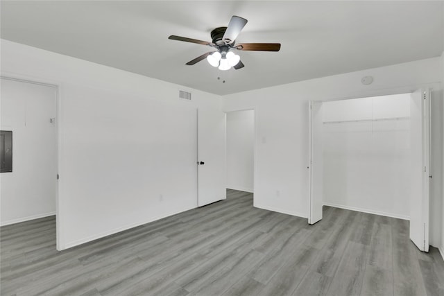 unfurnished bedroom with ceiling fan, light wood-type flooring, a closet, and electric panel