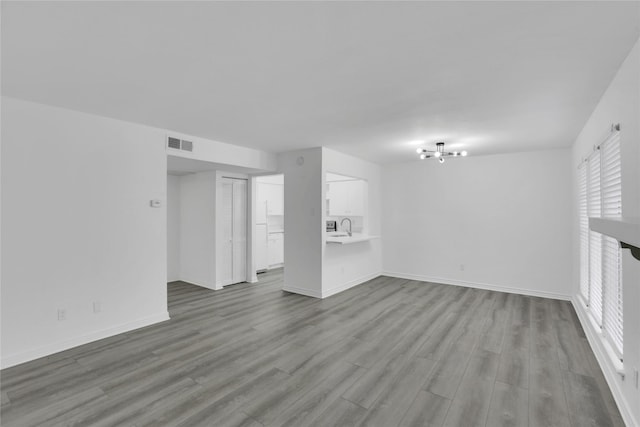 unfurnished living room with light hardwood / wood-style flooring, a chandelier, and sink