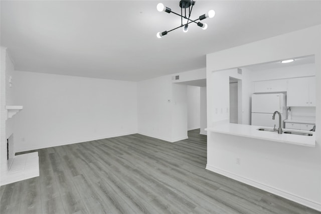 unfurnished living room with an inviting chandelier, wood-type flooring, and sink