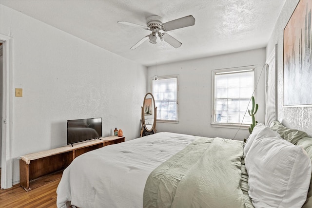 bedroom featuring wood-type flooring, a textured ceiling, and ceiling fan