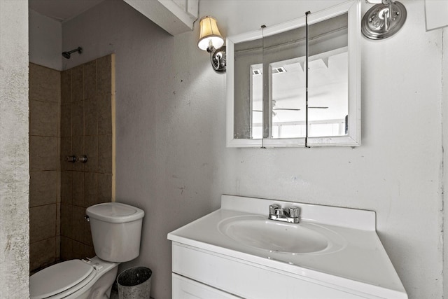 bathroom with vanity, toilet, and tiled shower