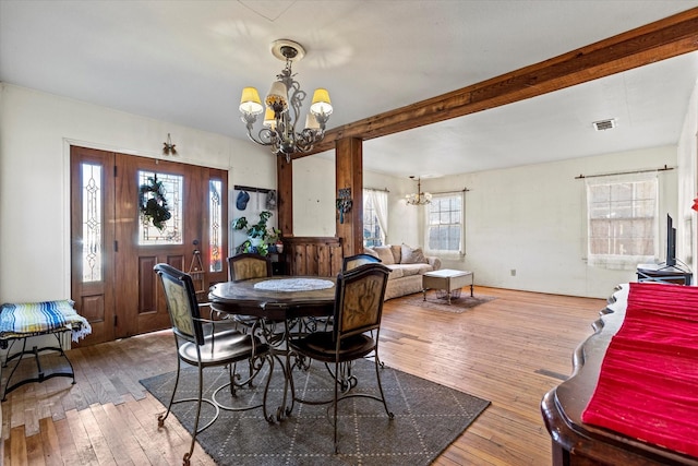 dining room featuring beam ceiling, hardwood / wood-style floors, and an inviting chandelier