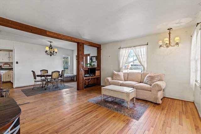 living room featuring beamed ceiling, a notable chandelier, and light hardwood / wood-style floors