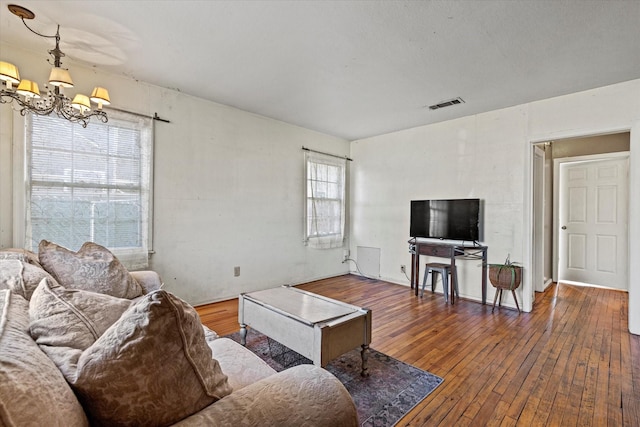 living room featuring wood-type flooring, a wealth of natural light, and a notable chandelier