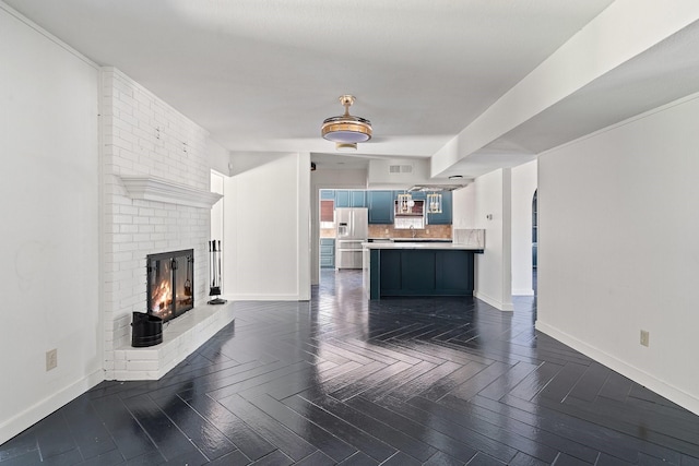 unfurnished living room with a brick fireplace and dark parquet floors