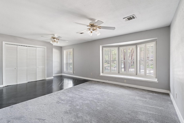 unfurnished bedroom with a textured ceiling, ceiling fan, dark parquet floors, and a closet