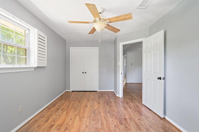 unfurnished bedroom with ceiling fan, light wood-type flooring, and a closet