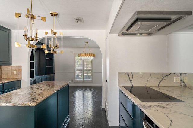 kitchen with dark parquet flooring, hanging light fixtures, backsplash, and light stone countertops