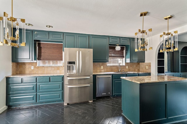 kitchen with appliances with stainless steel finishes, hanging light fixtures, decorative backsplash, and sink