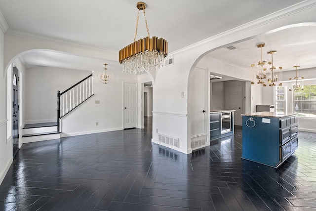 interior space with dark parquet flooring, ornamental molding, and a notable chandelier