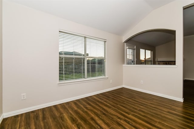 spare room with dark wood-type flooring and lofted ceiling