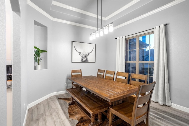 dining space featuring ornamental molding, a tray ceiling, and wood-type flooring