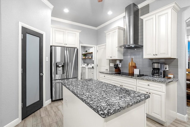 kitchen featuring a kitchen island, stainless steel fridge, wall chimney exhaust hood, and white cabinetry