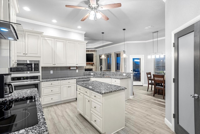 kitchen with kitchen peninsula, a center island, hanging light fixtures, and stainless steel appliances