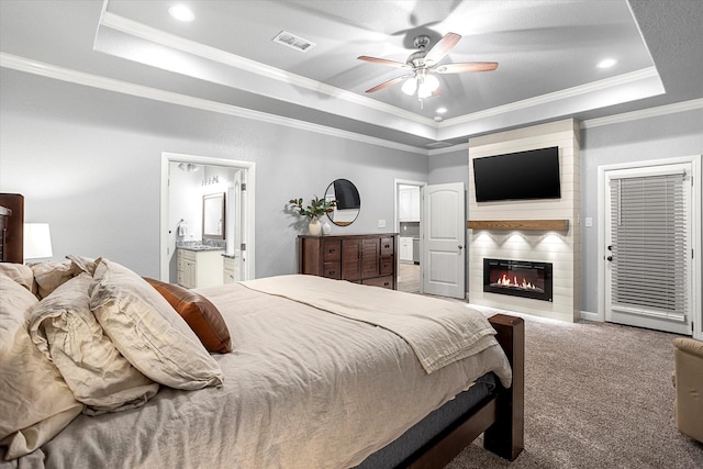 bedroom featuring a raised ceiling, carpet floors, a large fireplace, and ornamental molding