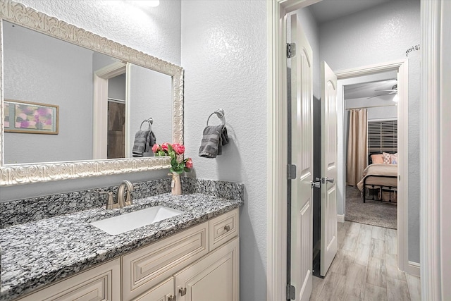 bathroom with hardwood / wood-style flooring, ceiling fan, and vanity