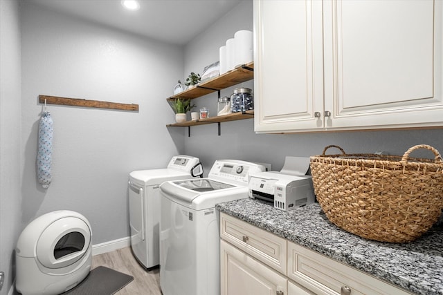 laundry area with washer and dryer, light wood-type flooring, and cabinets