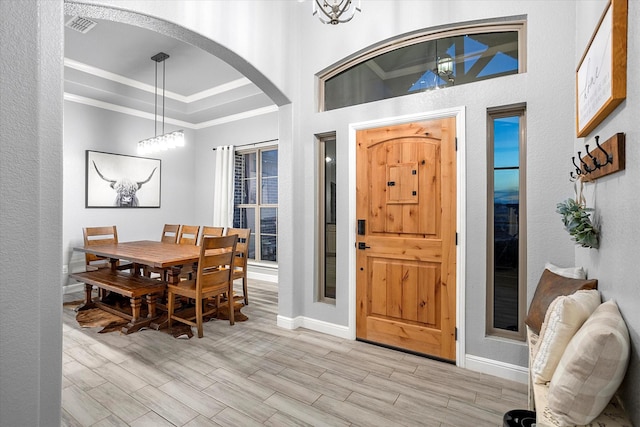 foyer featuring ornamental molding, a notable chandelier, and a tray ceiling