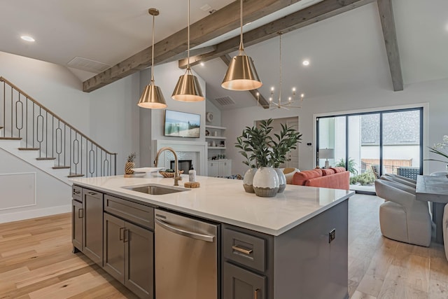 kitchen with hanging light fixtures, an island with sink, sink, light hardwood / wood-style flooring, and stainless steel dishwasher