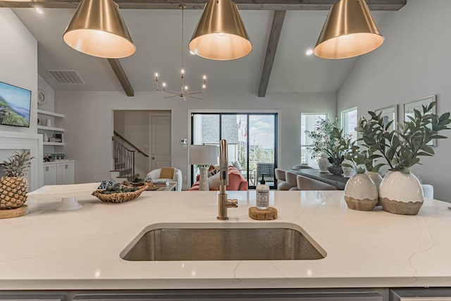 kitchen featuring sink, vaulted ceiling with beams, built in features, hanging light fixtures, and light stone countertops