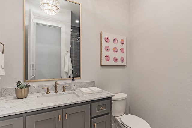 bathroom with toilet, a notable chandelier, and vanity