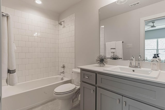 full bathroom with toilet, tiled shower / bath combo, ceiling fan, and vanity