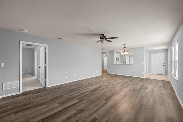 unfurnished living room featuring ceiling fan with notable chandelier and hardwood / wood-style floors