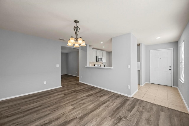 unfurnished living room featuring wood-type flooring and a notable chandelier