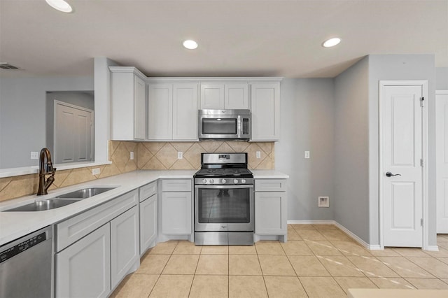 kitchen with light tile patterned floors, tasteful backsplash, white cabinets, appliances with stainless steel finishes, and sink