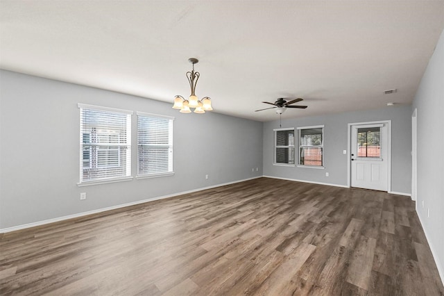 unfurnished living room featuring dark hardwood / wood-style flooring and ceiling fan with notable chandelier