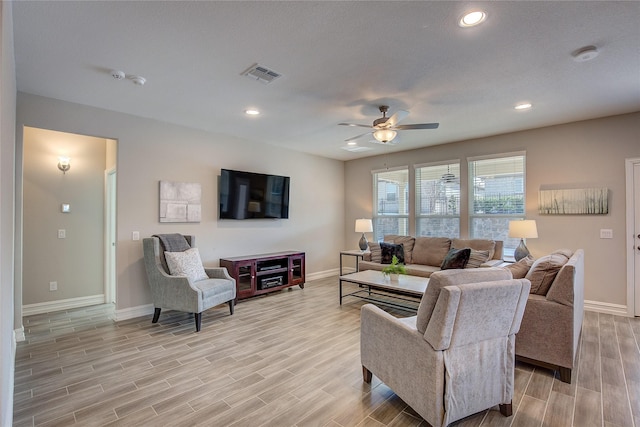 living area with visible vents, baseboards, a ceiling fan, and wood finish floors